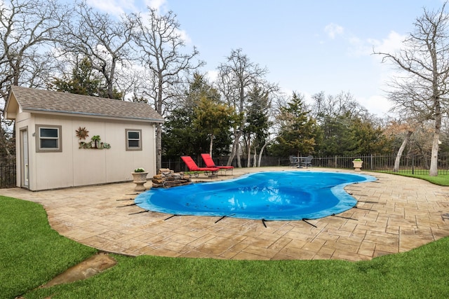 view of pool with an outdoor structure, a patio area, a fenced backyard, and a fenced in pool