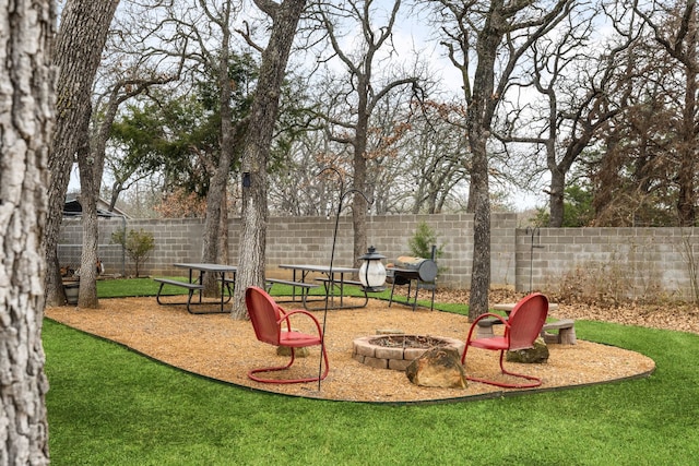 view of play area with a yard, an outdoor fire pit, and a fenced backyard