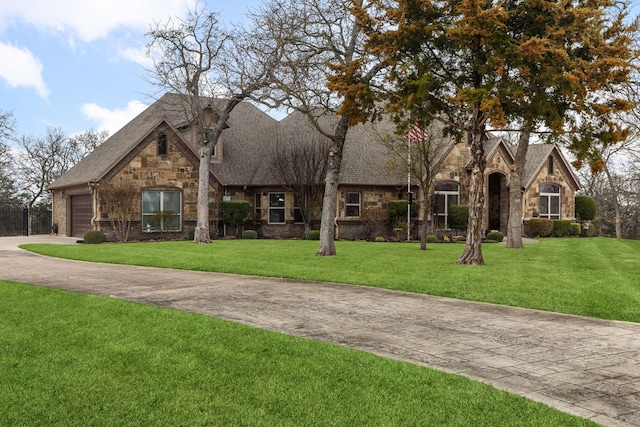 view of front facade featuring a garage, stone siding, a shingled roof, and a front lawn