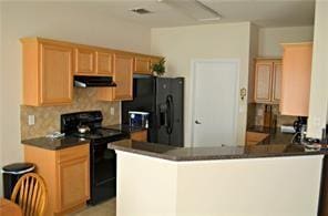 kitchen featuring range hood, tasteful backsplash, dark countertops, a peninsula, and black appliances