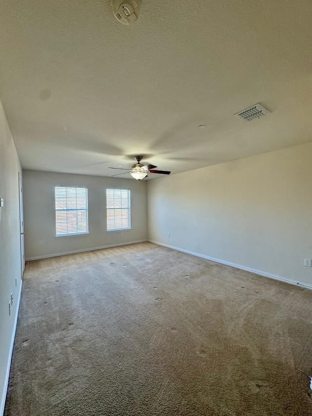 empty room with light carpet, baseboards, visible vents, and a textured ceiling