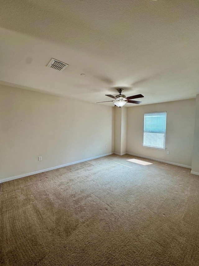 carpeted spare room with a ceiling fan, baseboards, visible vents, and a textured ceiling