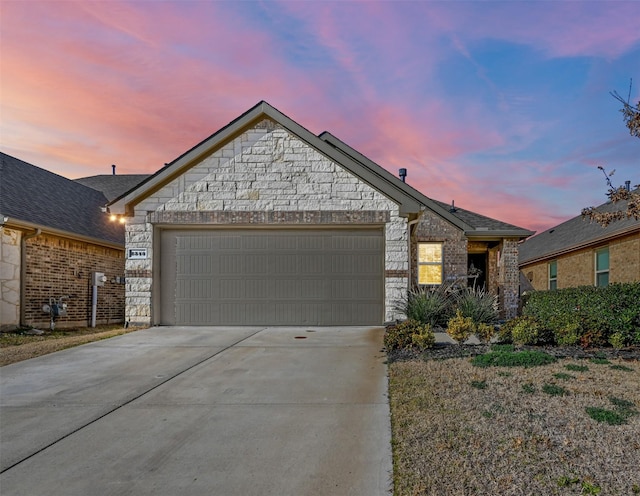 view of front facade with a garage, concrete driveway, brick siding, and stone siding