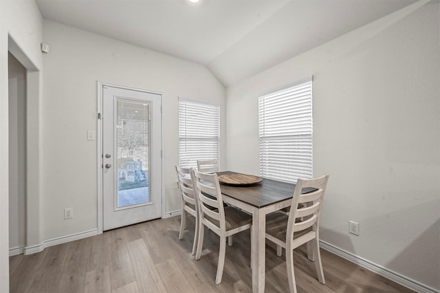 dining area with vaulted ceiling, light wood-type flooring, and baseboards