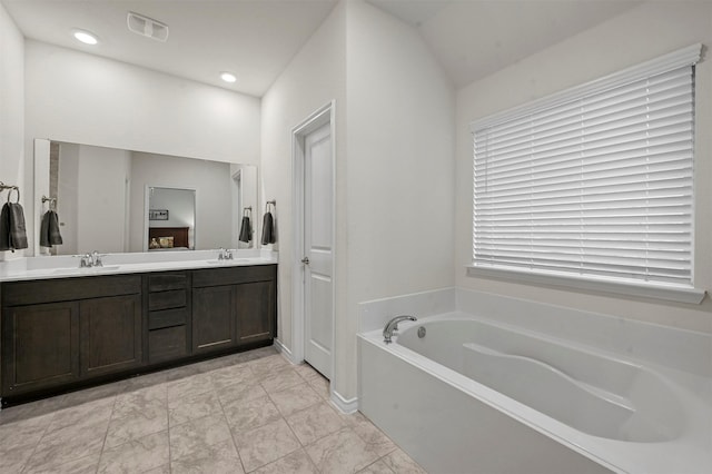 bathroom with visible vents, a sink, a bath, and double vanity