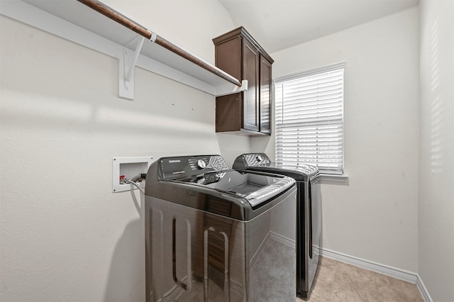 laundry area featuring washing machine and clothes dryer, cabinet space, and baseboards