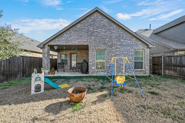 back of house with a playground, a patio, a fenced backyard, and brick siding