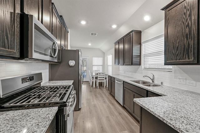 kitchen with light stone counters, stainless steel appliances, a sink, visible vents, and dark brown cabinets