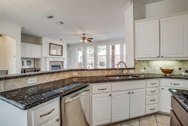 kitchen with arched walkways, light tile patterned flooring, a sink, backsplash, and dishwasher