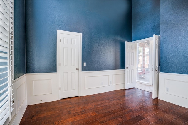 empty room with a wainscoted wall, a textured wall, and hardwood / wood-style floors