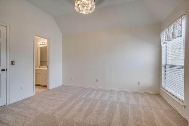 unfurnished room with a chandelier, light colored carpet, a sink, baseboards, and vaulted ceiling