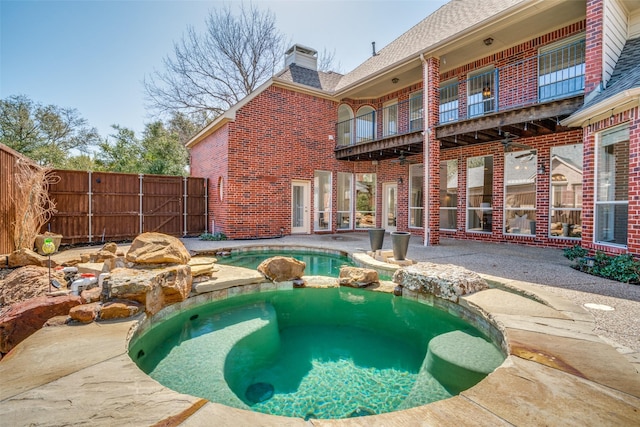 view of swimming pool with a patio area, a pool with connected hot tub, and fence