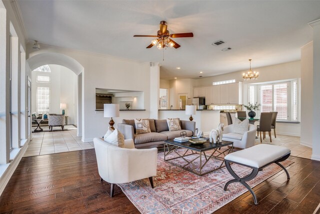 living room featuring light wood-style floors, baseboards, visible vents, and arched walkways