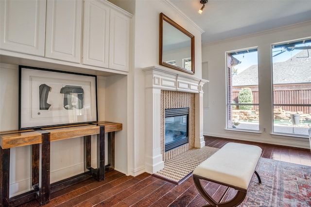 interior space featuring crown molding, baseboards, wood finished floors, and a tile fireplace