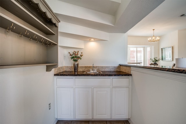 kitchen with dark stone counters, open shelves, a sink, and white cabinetry