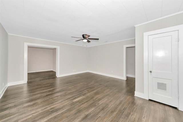 spare room featuring dark wood-style flooring, crown molding, visible vents, a ceiling fan, and baseboards