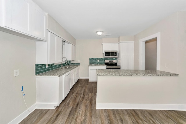 kitchen with dark wood-type flooring, appliances with stainless steel finishes, backsplash, and a sink