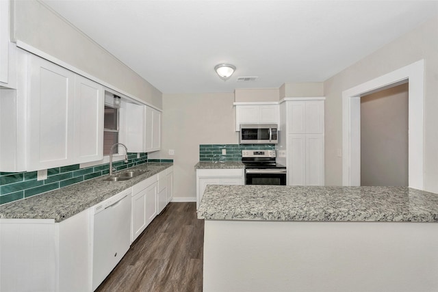 kitchen with visible vents, dark wood-style flooring, a sink, stainless steel appliances, and backsplash