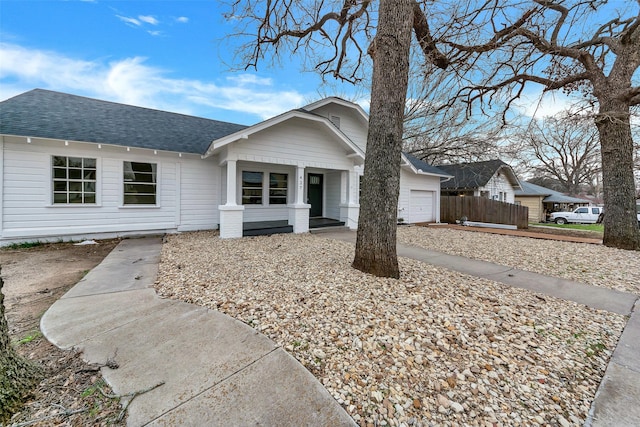 ranch-style house with an attached garage, fence, and roof with shingles