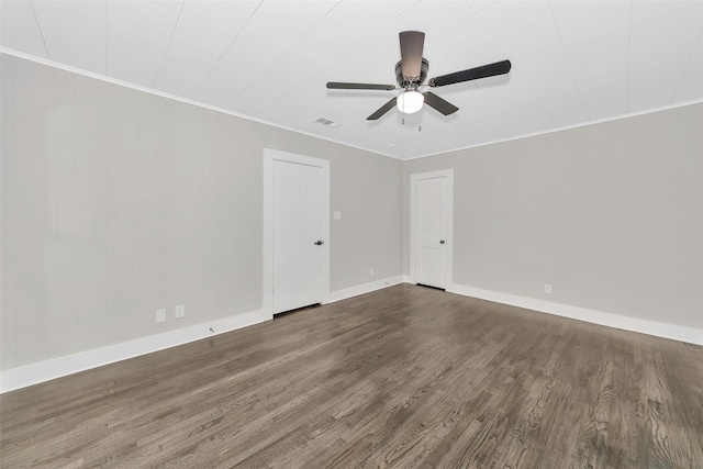 spare room with baseboards, dark wood finished floors, visible vents, and crown molding