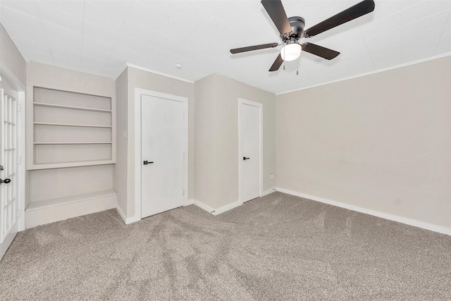 interior space featuring carpet, crown molding, baseboards, and a ceiling fan