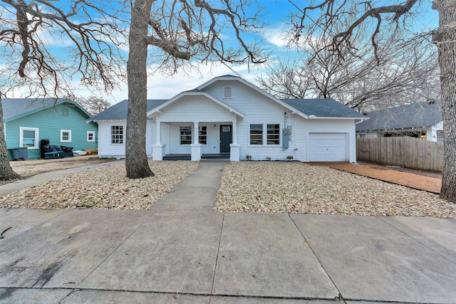 view of front of home with a shingled roof, covered porch, concrete driveway, fence, and a garage