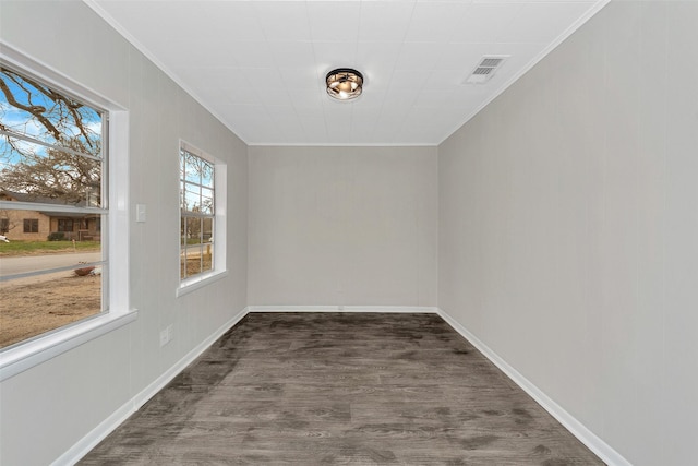 unfurnished room with baseboards, visible vents, dark wood-type flooring, and ornamental molding