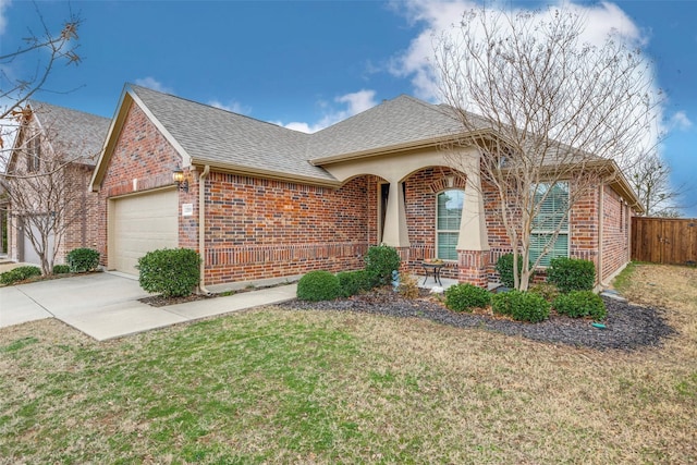 ranch-style home featuring an attached garage, a shingled roof, fence, and brick siding