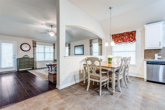 dining area featuring a ceiling fan, light tile patterned flooring, vaulted ceiling, and baseboards