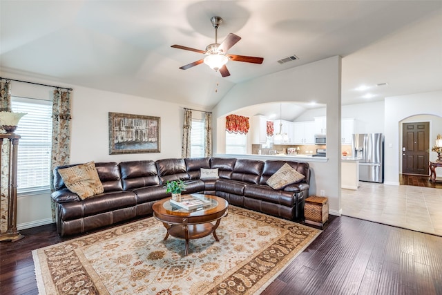 living room featuring visible vents, arched walkways, a ceiling fan, dark wood-style floors, and vaulted ceiling