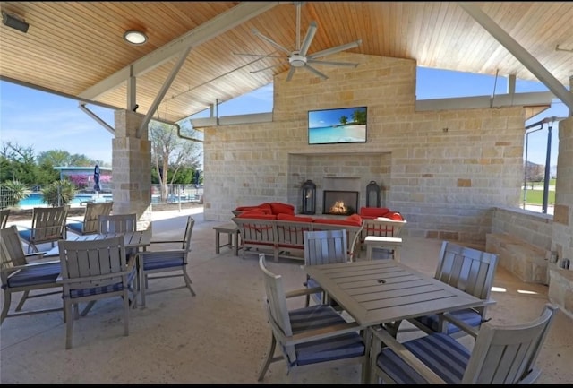 view of patio / terrace with outdoor dining space, a large fireplace, and ceiling fan