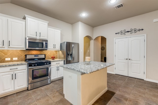 kitchen with tasteful backsplash, visible vents, arched walkways, a center island, and stainless steel appliances