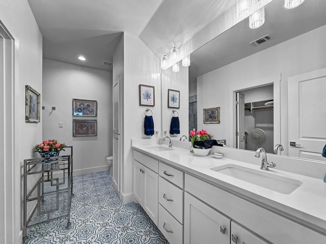 bathroom with toilet, double vanity, visible vents, and a sink