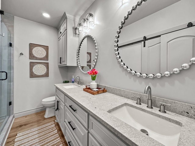 bathroom featuring wood finished floors, a stall shower, a sink, and toilet