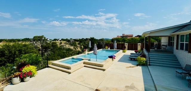 pool with a patio area, a fenced backyard, and an in ground hot tub