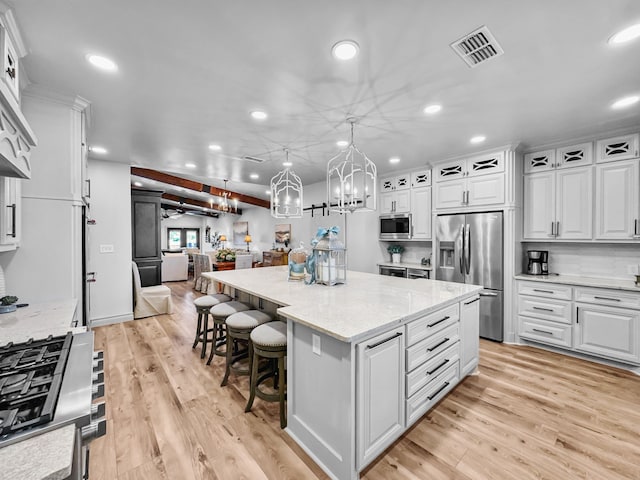 kitchen with light wood finished floors, visible vents, white cabinets, a spacious island, and appliances with stainless steel finishes