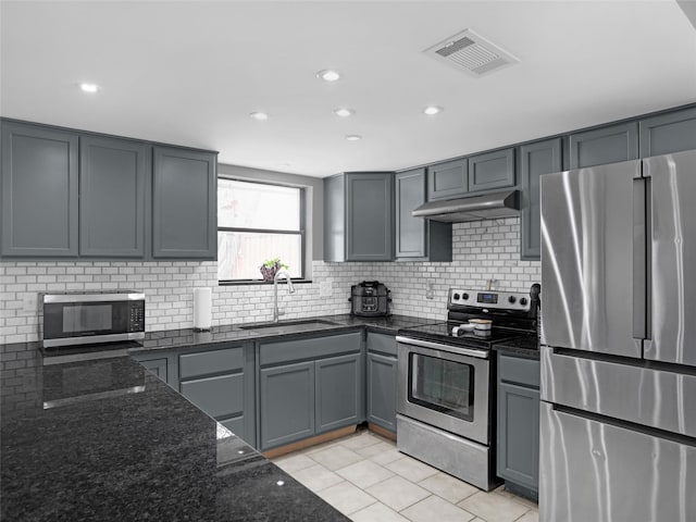 kitchen with visible vents, dark stone counters, appliances with stainless steel finishes, under cabinet range hood, and a sink