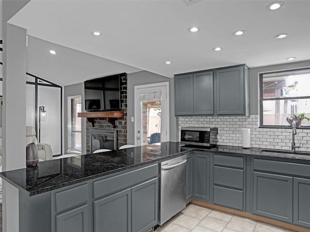 kitchen featuring stainless steel appliances, a sink, a peninsula, and gray cabinetry