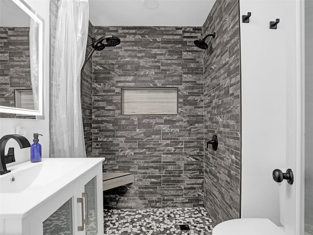 full bathroom with toilet, a tile shower, and vanity