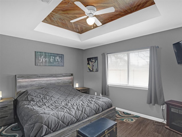 bedroom featuring baseboards, wood ceiling, ceiling fan, wood finished floors, and a tray ceiling