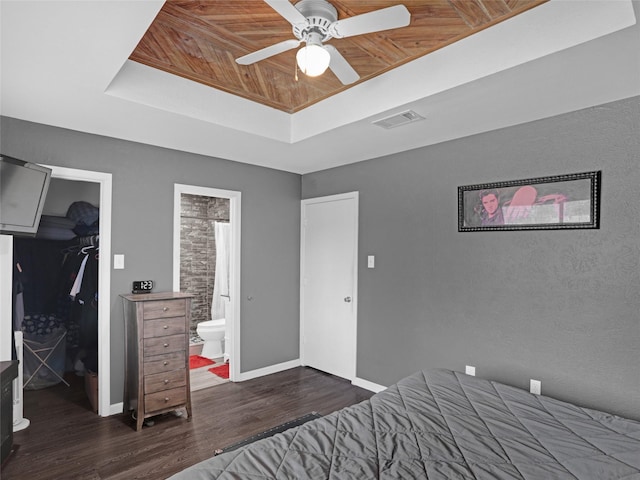 bedroom featuring a closet, a raised ceiling, visible vents, a spacious closet, and wood finished floors