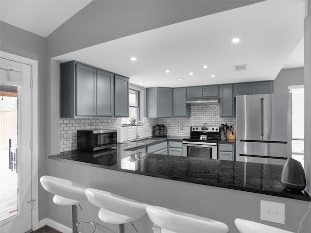 1709 Broadway St, Denton, TX 76201 - kitchen featuring decorative backsplash, stainless steel appliances, under cabinet range hood, a sink, and baseboards