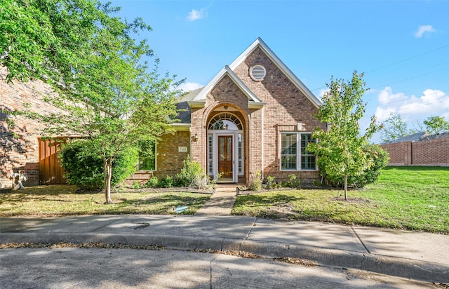 traditional home with brick siding, fence, and a front lawn