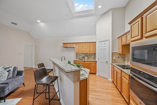 kitchen featuring light wood-style floors, built in microwave, oven, and visible vents