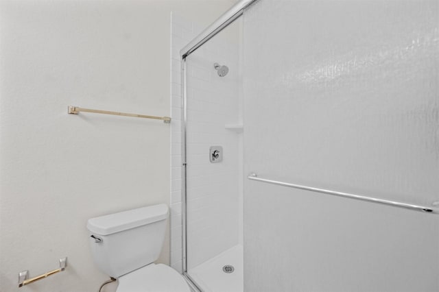 bathroom with a tile shower and toilet