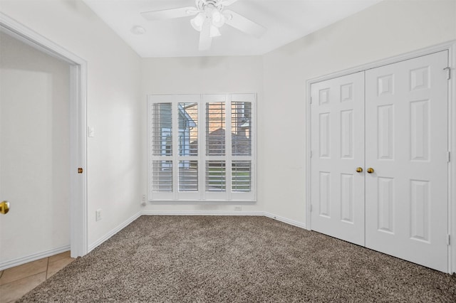 unfurnished bedroom with carpet, tile patterned floors, a ceiling fan, and baseboards