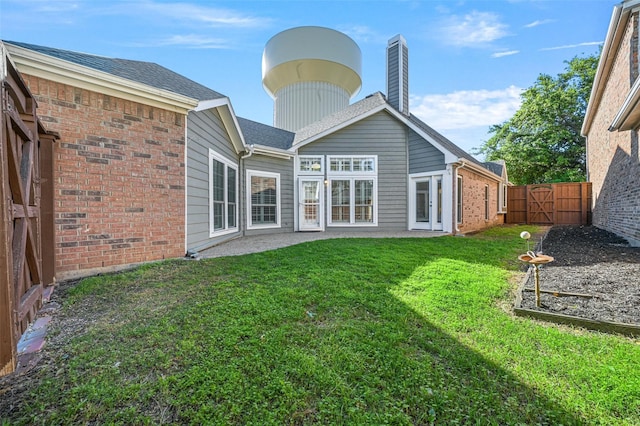 rear view of house with fence private yard, brick siding, a yard, and a chimney