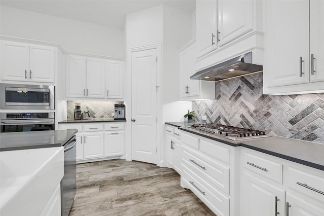 kitchen featuring under cabinet range hood, white cabinetry, stainless steel appliances, and dark countertops