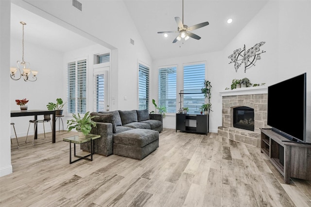 living room with visible vents, ceiling fan with notable chandelier, a fireplace, and light wood-style floors