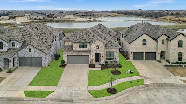 french country style house with a front lawn, a water view, driveway, and roof with shingles